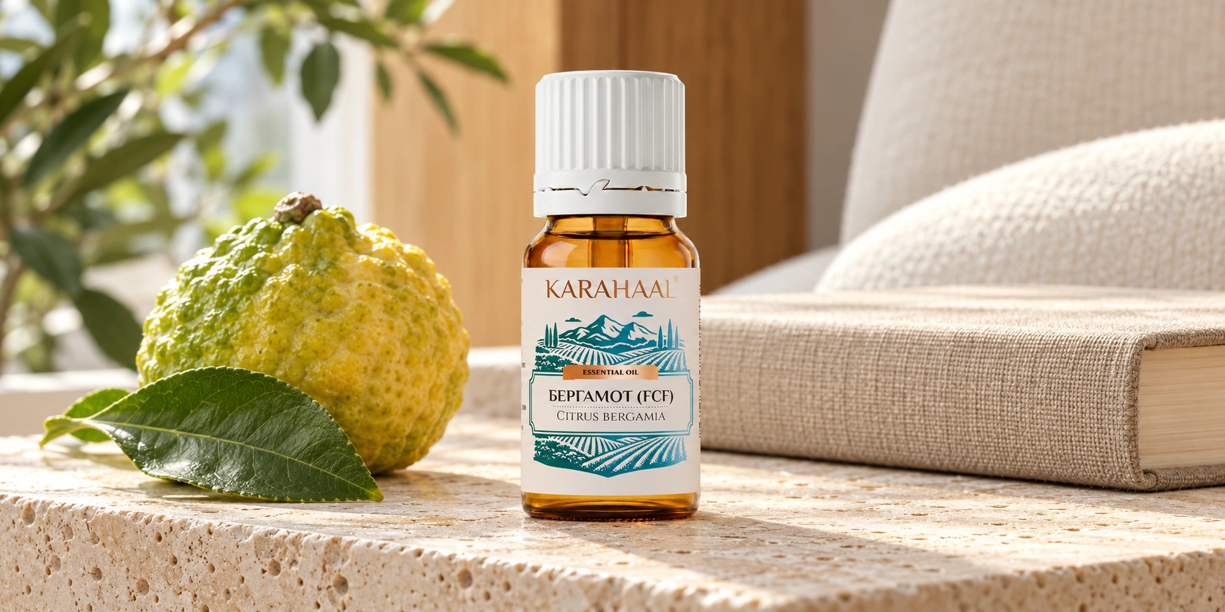 Флакон Karahaal «Бергамот (FCF)» с оригинальной этикеткой на светлом камне рядом с цитрусовым плодом и закрытой книгой.